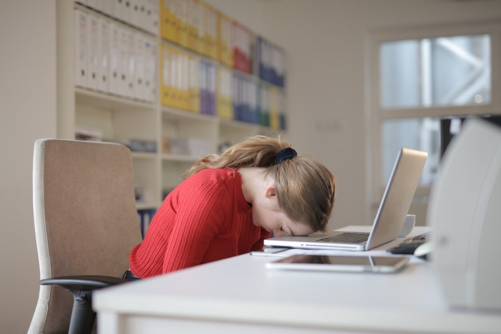 tired woman leaning her head against her computer to demonstrate her emotional or winter fatigue