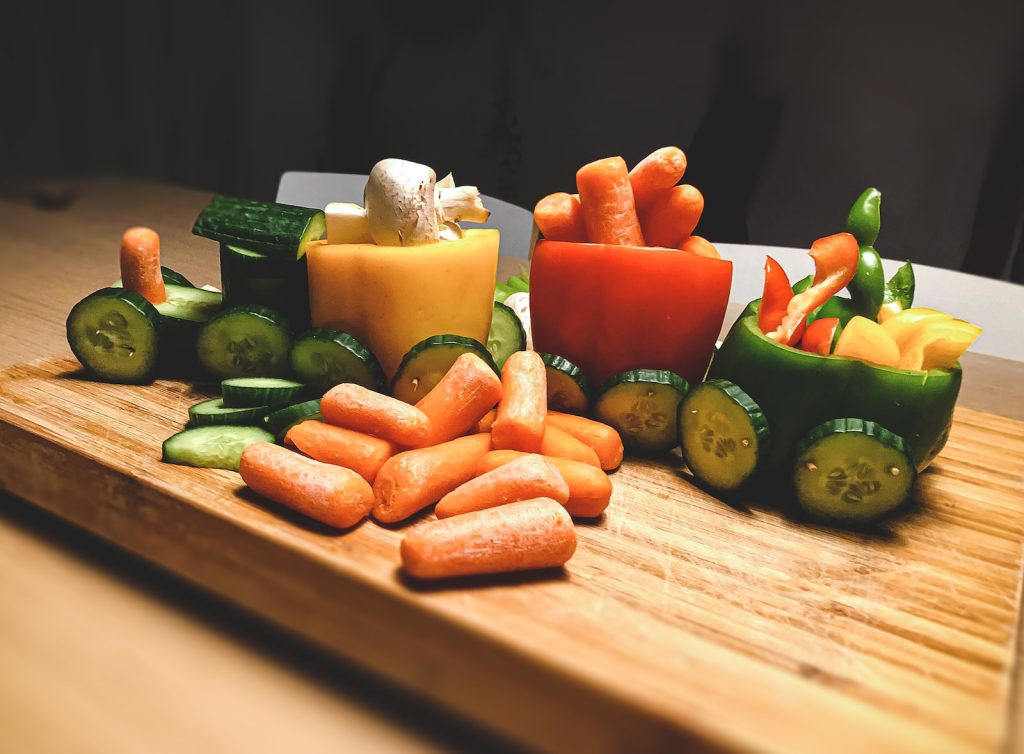 sliced ​​carrots and green peppers on a brown wooden cutting board