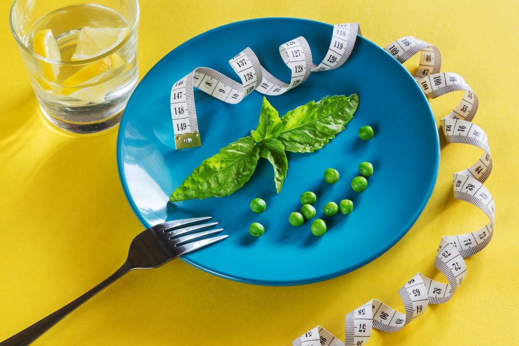 a blue plate garnished with green vegetables and a tape measure