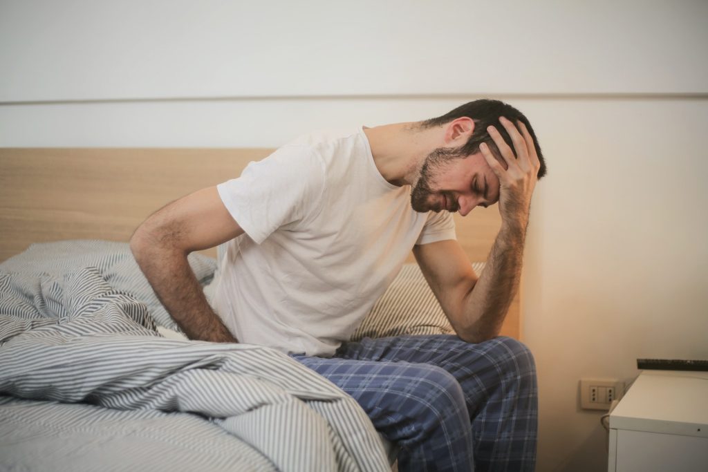 Young man in pajamas suffering from headache in the morning